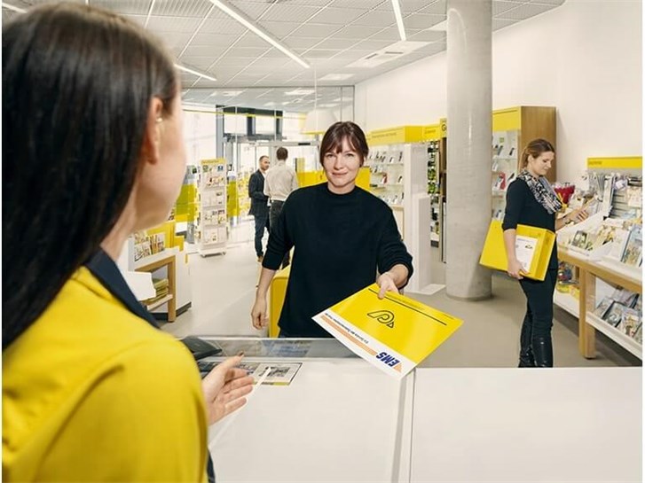 Post Mitarbeiter mit Kunde in Filiale, Paket und EMS.